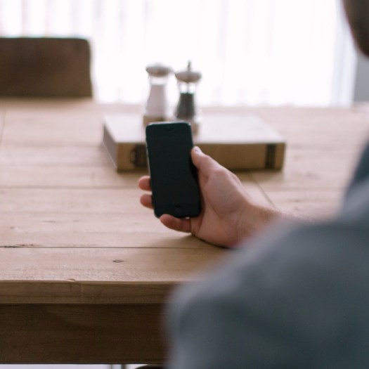 cropped-person-smartphone-office-table1